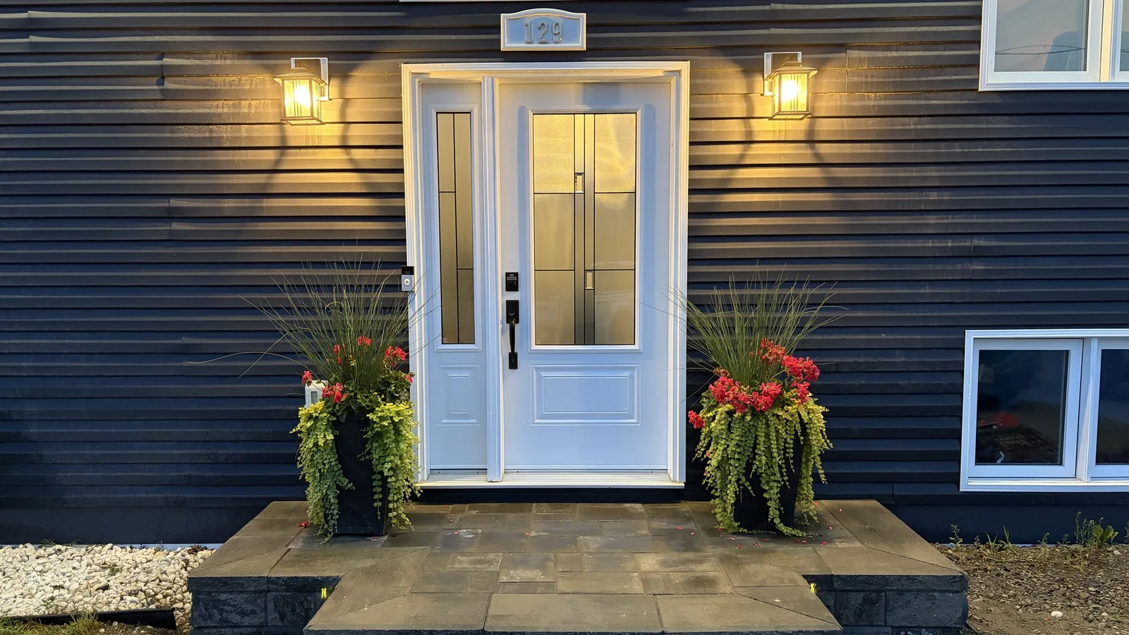 Evening paver front entrance with stone steps and lantern lighting, built by Edwards Landscape and Construction in North Bay